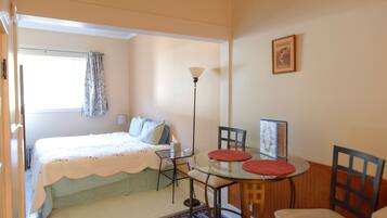 A bedroom with a bed, a bedside table, a lamp, and a window with curtains.