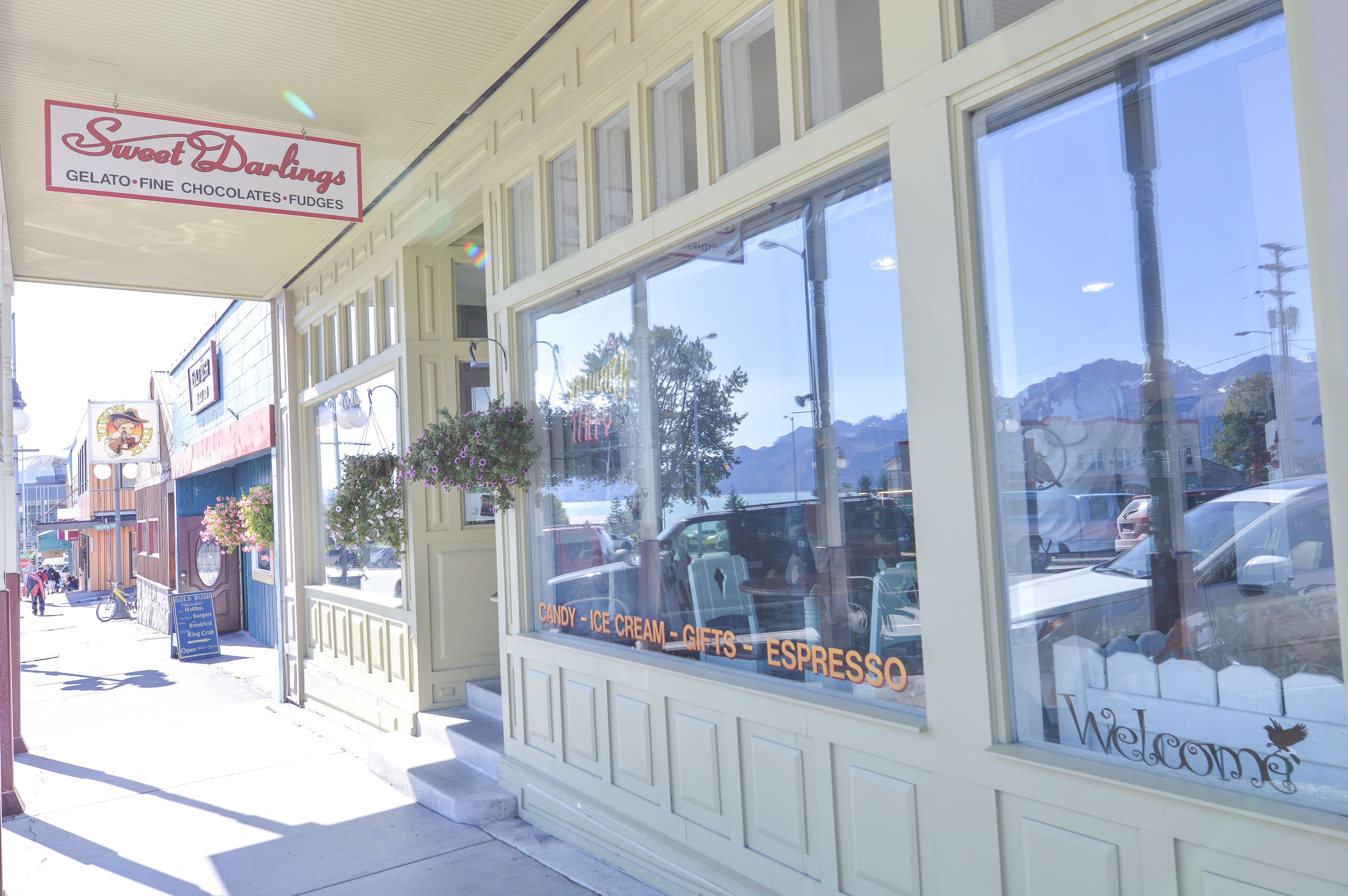 A storefront with a sign reading "Sweet Darlings" offering gelato, fine chocolates, and fudges.