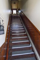 Una escalera de madera con barandilla que sube a un piso superior.