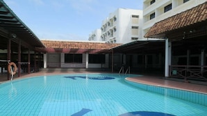 A swimming pool with a tiled floor and a handprint design, surrounded by covered areas and a building with a tiled roof. - Seaview Hotel (Bandar Seri Begawan)