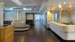 A hotel lobby with a reception desk, seating area, and a hallway leading to other rooms. - Seaview Hotel (Bandar Seri Begawan)