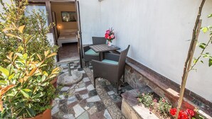 A small outdoor seating area with wicker furniture, a stone-tiled floor, and potted plants. - Apartment Divna (Rovinj)