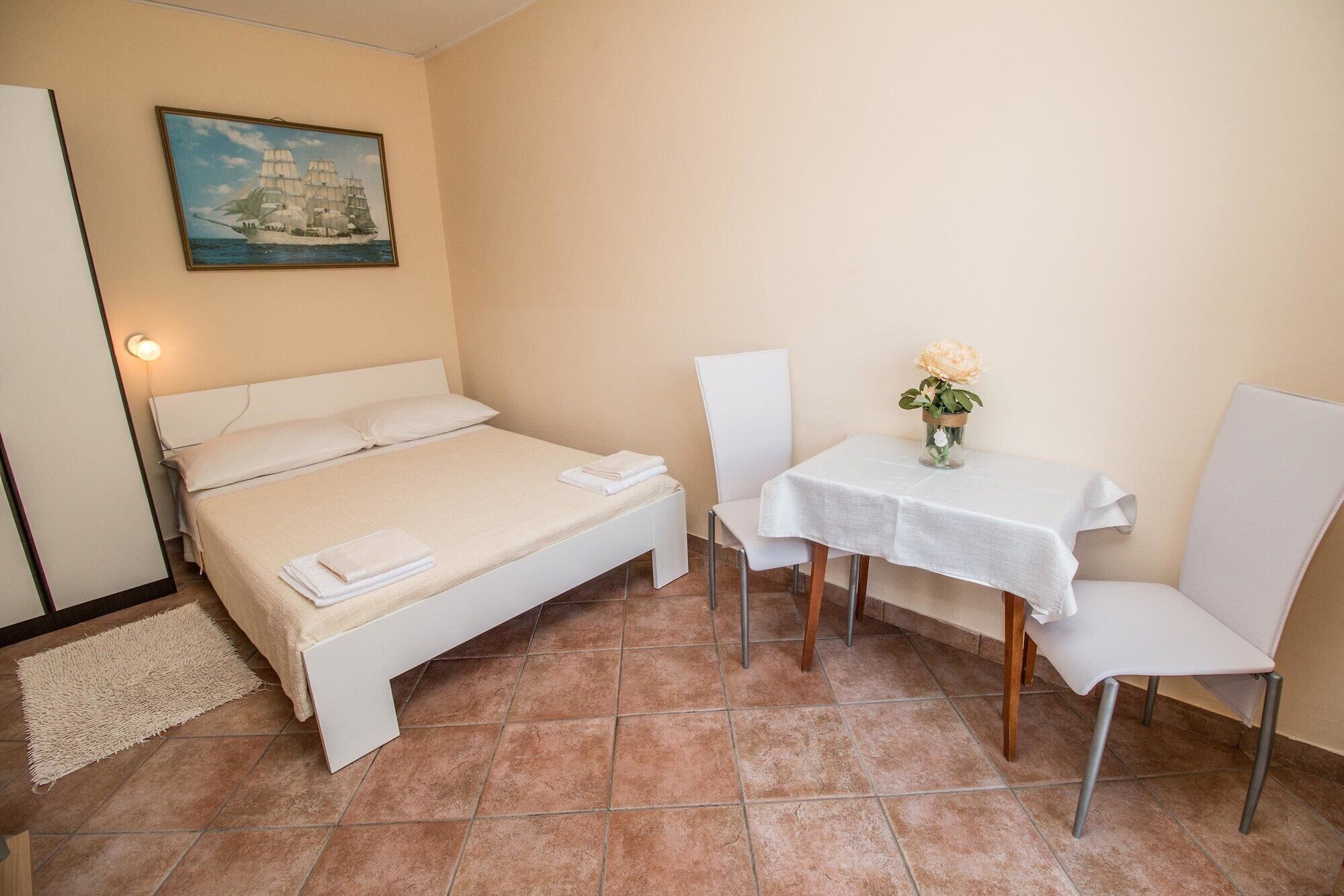A bedroom with a bed, a chair, a table, and a painting on the wall.