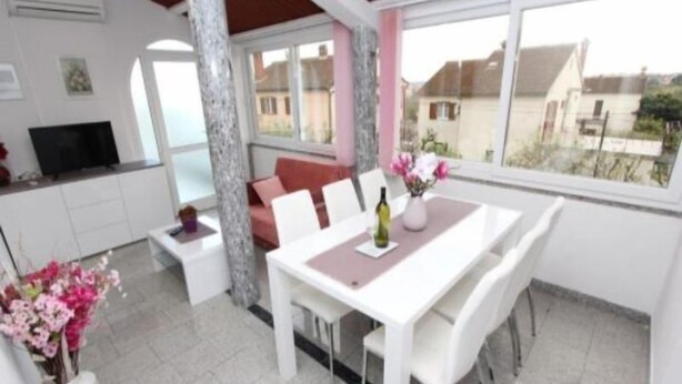 A modern living room with a dining area, white furniture, a large window, and a TV. - Apartment Divna (Rovinj)