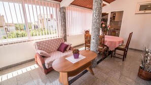 A cozy room with a sofa, a wooden table, and a dining area. - Apartment Divna (Rovinj)
