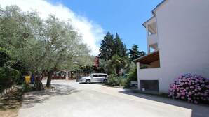 A residential street with a white building, parked cars, and trees. - Apartment Sena (Rovinj)