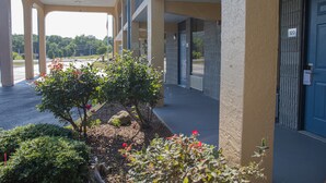 A building with a covered entrance, numbered 120, and a landscaped area with shrubs and flowers. - Grand Vista Hotel (Helenwood)