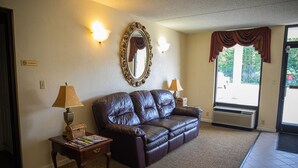 A living room with a leather sofa, two lamps, a mirror, and a door leading outside. - Grand Vista Hotel (Helenwood)