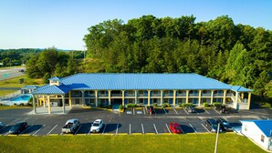 A motel with a blue roof, multiple balconies, and a parking lot with several cars. - Grand Vista Hotel (Helenwood)
