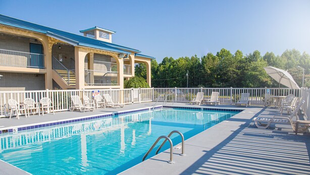A swimming pool with lounge chairs and a covered seating area. - Grand Vista Hotel (Helenwood)