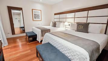 Una habitación de hotel con dos camas, un banco, un espejo y un cuadro en la pared.