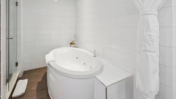 A modern bathroom with a large bathtub, white tiles, and a glass shower enclosure.