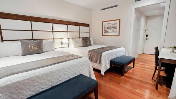 A hotel room with two beds, a bench, a dining table, and a framed picture on the wall. - Central Hotel Panama Casco Viejo (Panama City)
