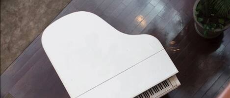 Un piano en una habitación con suelo de baldosas y una planta en maceta.