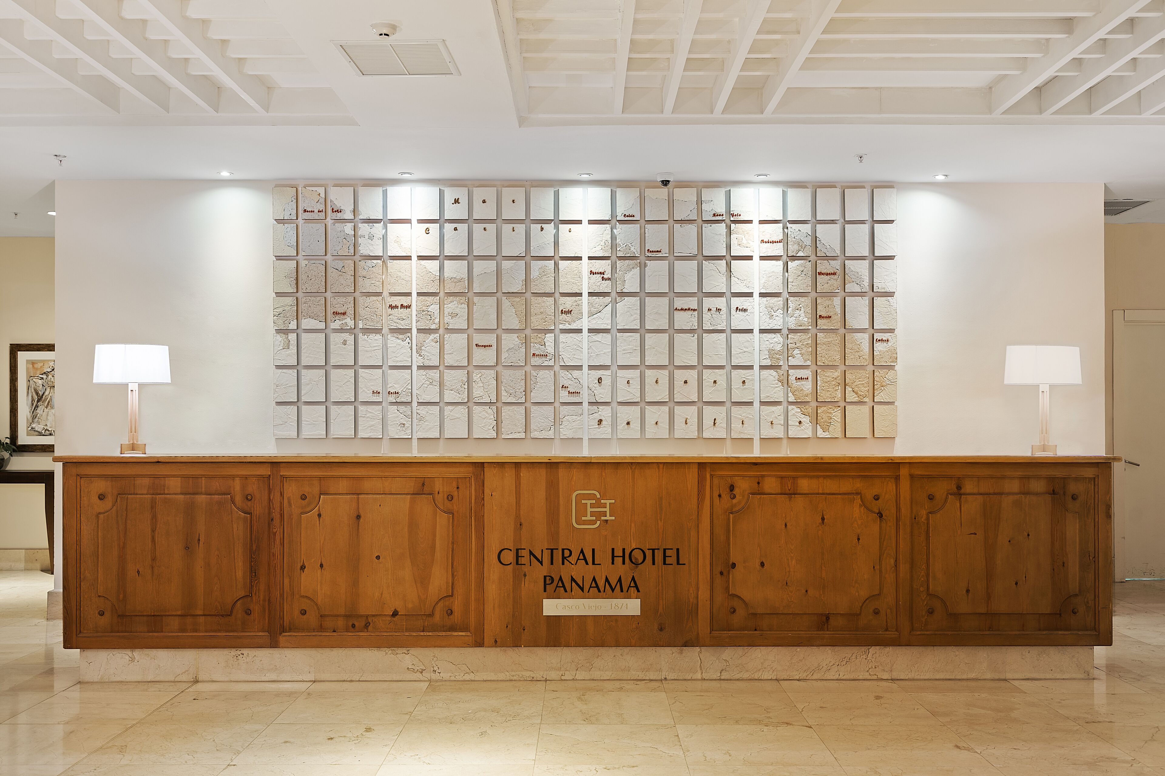 A reception desk with a wooden finish and a map display above it.