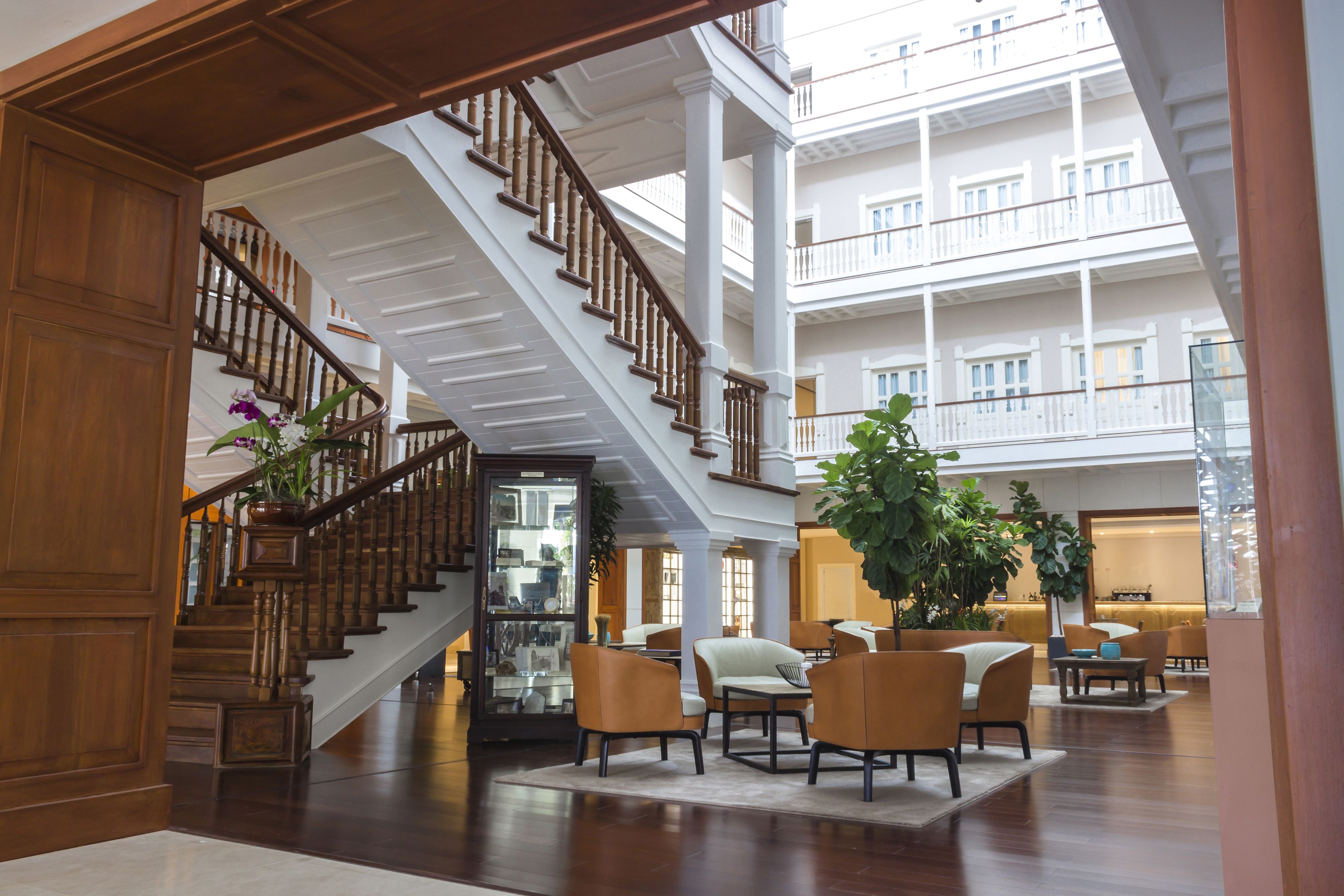 A spacious lobby with a grand staircase, comfortable seating areas, and a large indoor plant.