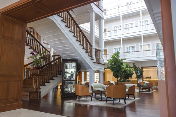 A spacious lobby with a grand staircase, comfortable seating areas, and a large indoor plant. - Central Hotel Panama Casco Viejo (Panama City)
