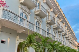 Un hotel de varios pisos con balcones, un cartel que dice 'Central' y abundante vegetación en la parte delantera.