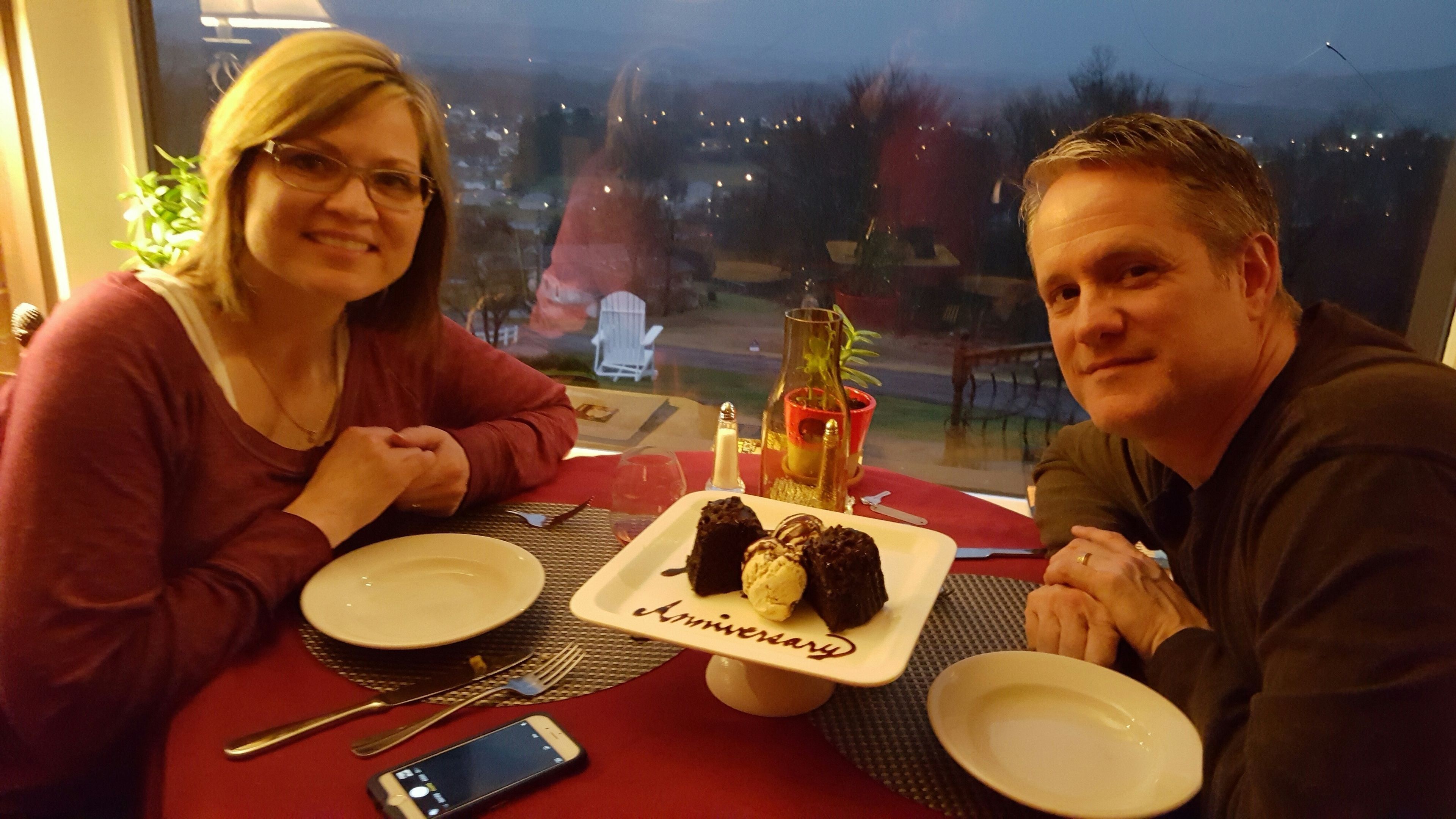 Een eettafel met een dessertborden, een kaars en een fles.