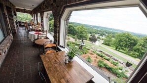 A restaurant with a long counter and multiple tables, large windows offering a view of a landscaped garden and distant hills. - The Inn at Dresden (Dresden)