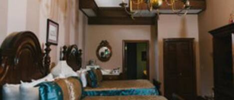 Ein traditionell eingerichtetes Schlafzimmer mit zwei Betten, einer Chandelüster und einem Holzschrank.