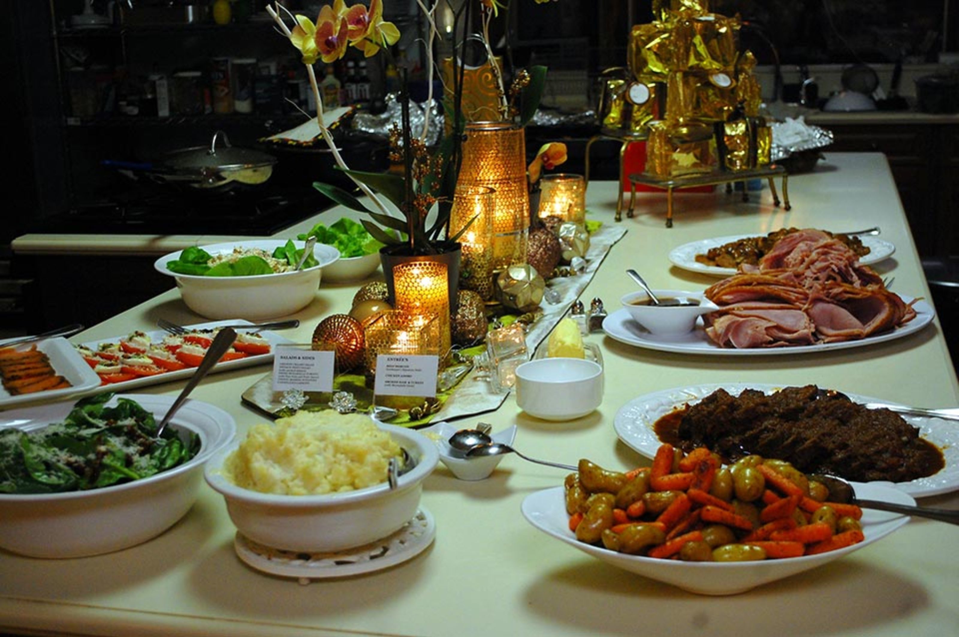Une table de buffet proposant une variété de plats, notamment des salades, des viandes et des légumes, agrémentée de bougies et d’objets décoratifs.