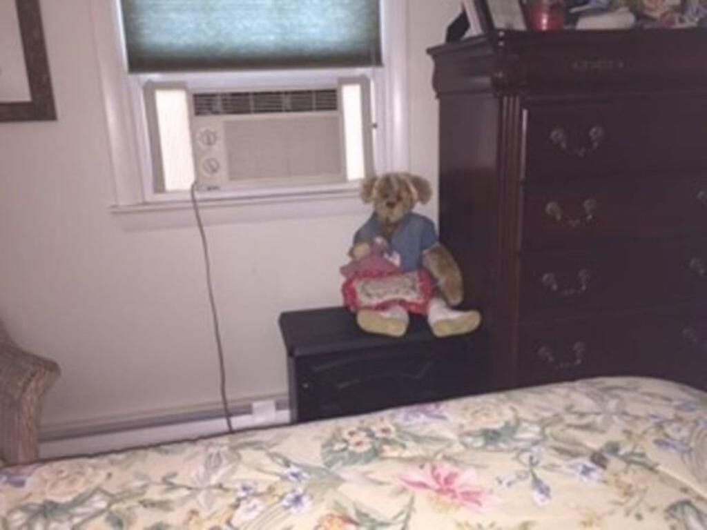 Une chambre avec un lit, une commode et une fenêtre avec des stores.