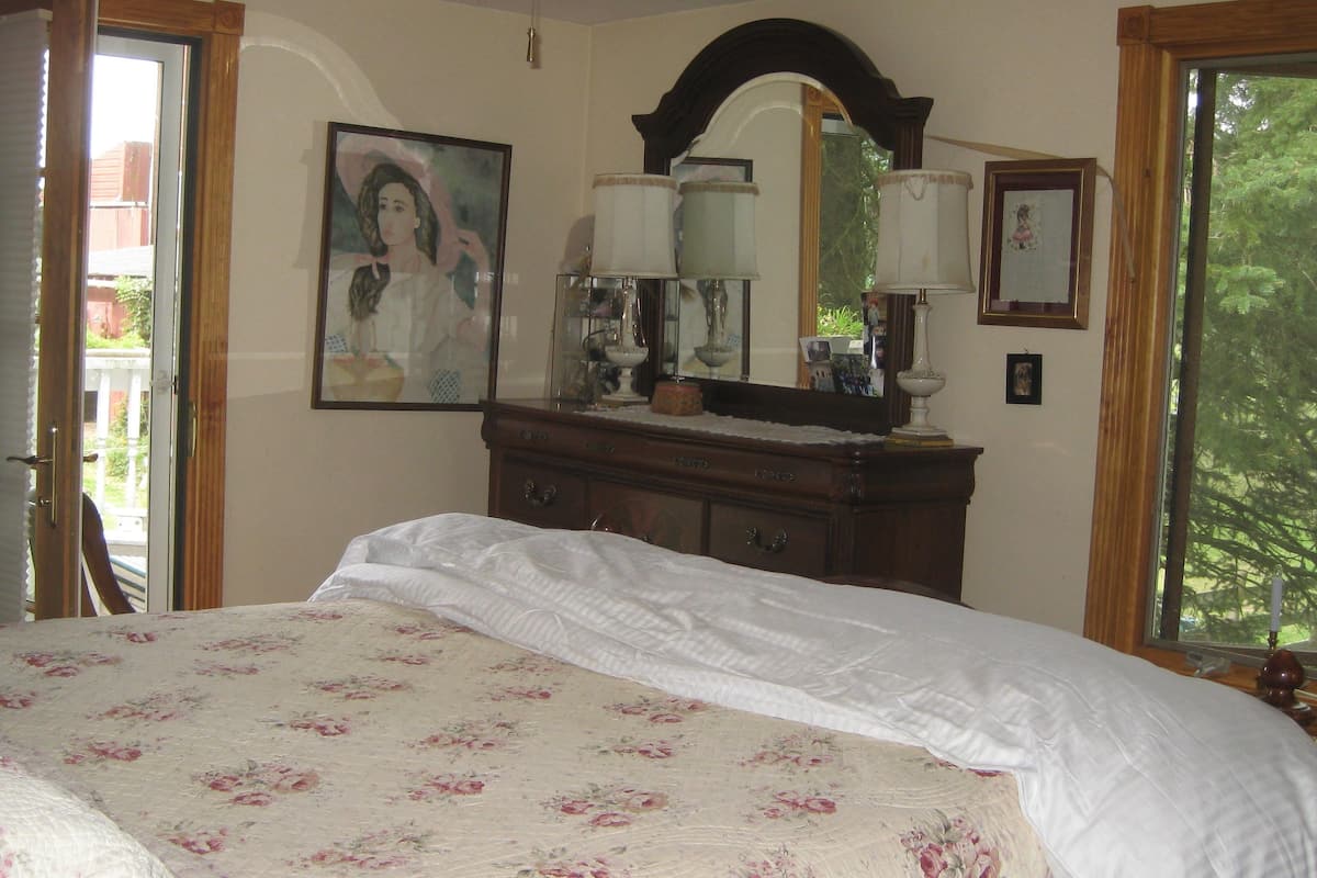 A bedroom with a bed, dresser, and a large window.