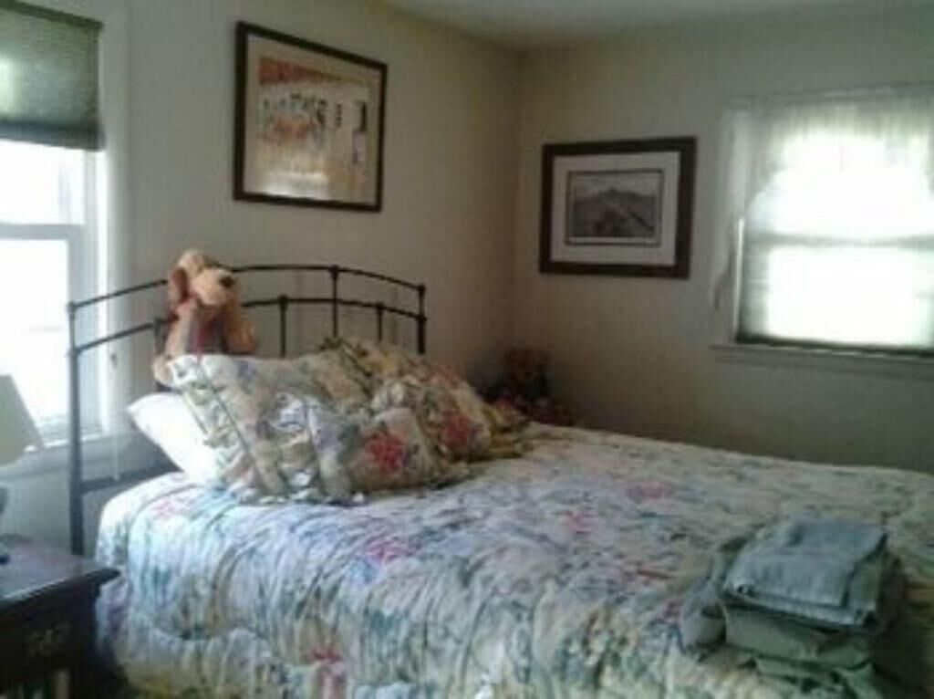 A bedroom with a bed, a nightstand, a lamp, and a window with curtains.