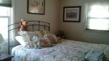 A bedroom with a bed, a nightstand, a lamp, and a window with curtains.