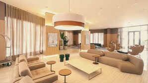 A modern living room with a large sofa, a coffee table, and a hanging light fixture. - TRYP by Wyndham Ribeirão Preto Nacional Inn (Ribeirão Preto)
