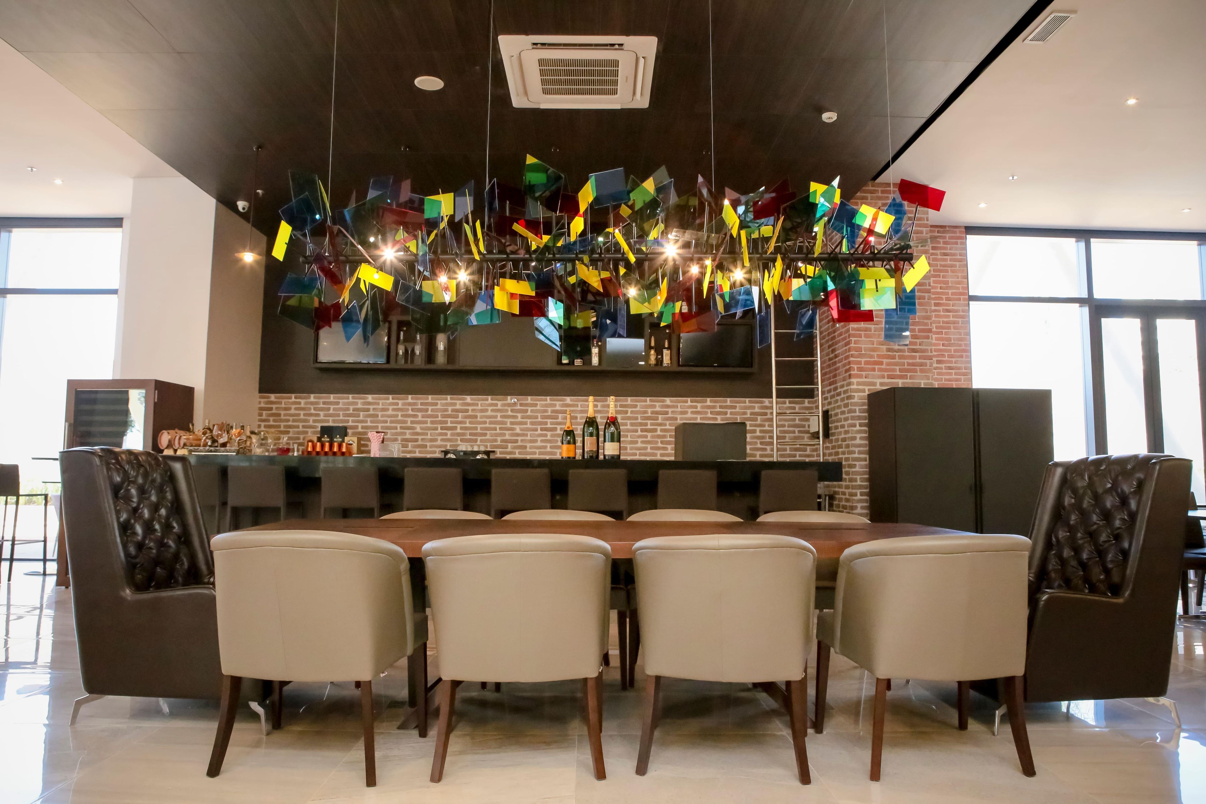 A modern dining area with a brick wall, a long table, and six chairs.