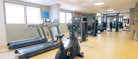 Une salle de sport équipée de tapis de course, de vélos elliptiques et de matériel de musculation.