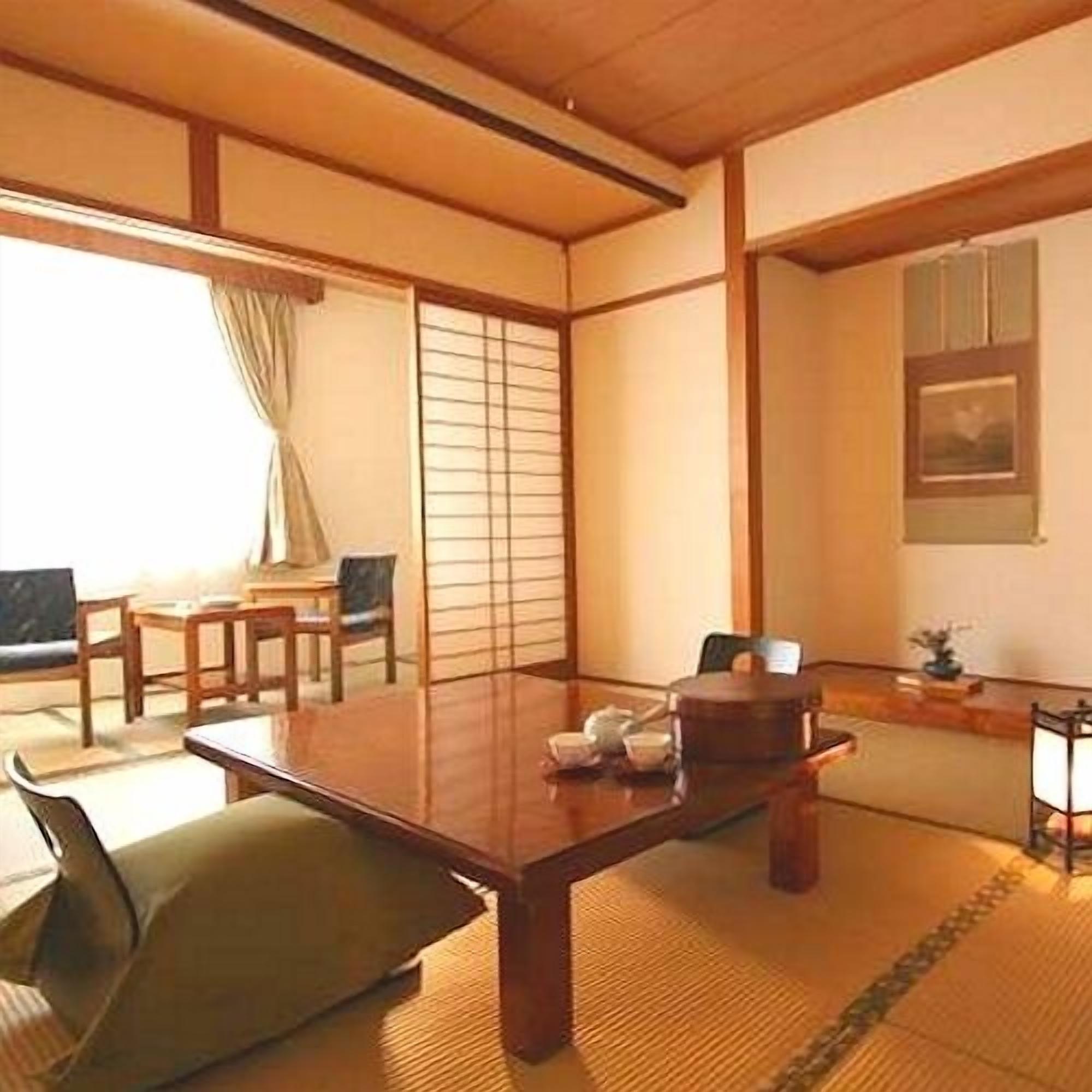 Ett traditionellt japanskt rum med tatamimattor på golvet, ett lågt bord och skjutdörrar.