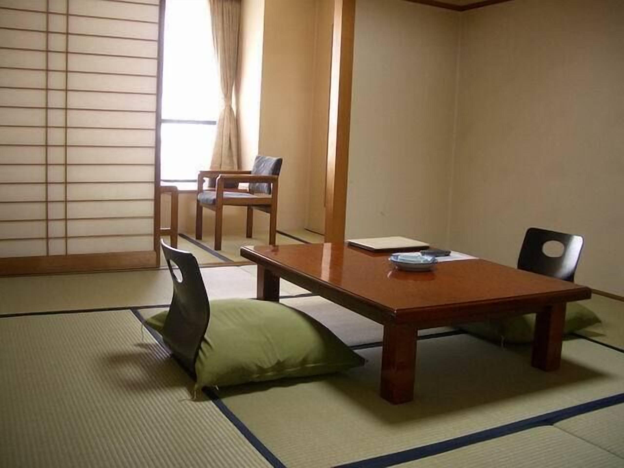 Ett traditionellt japanskt tatamirum med ett lågt träbord, två stolar och en futonmadrass.