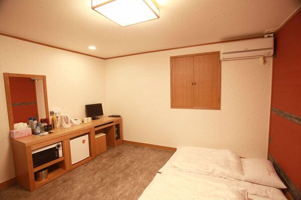 A hotel room with a bed, a wooden desk with a television, a microwave, and a small refrigerator. - La Nuit Hotel (Jeonju)