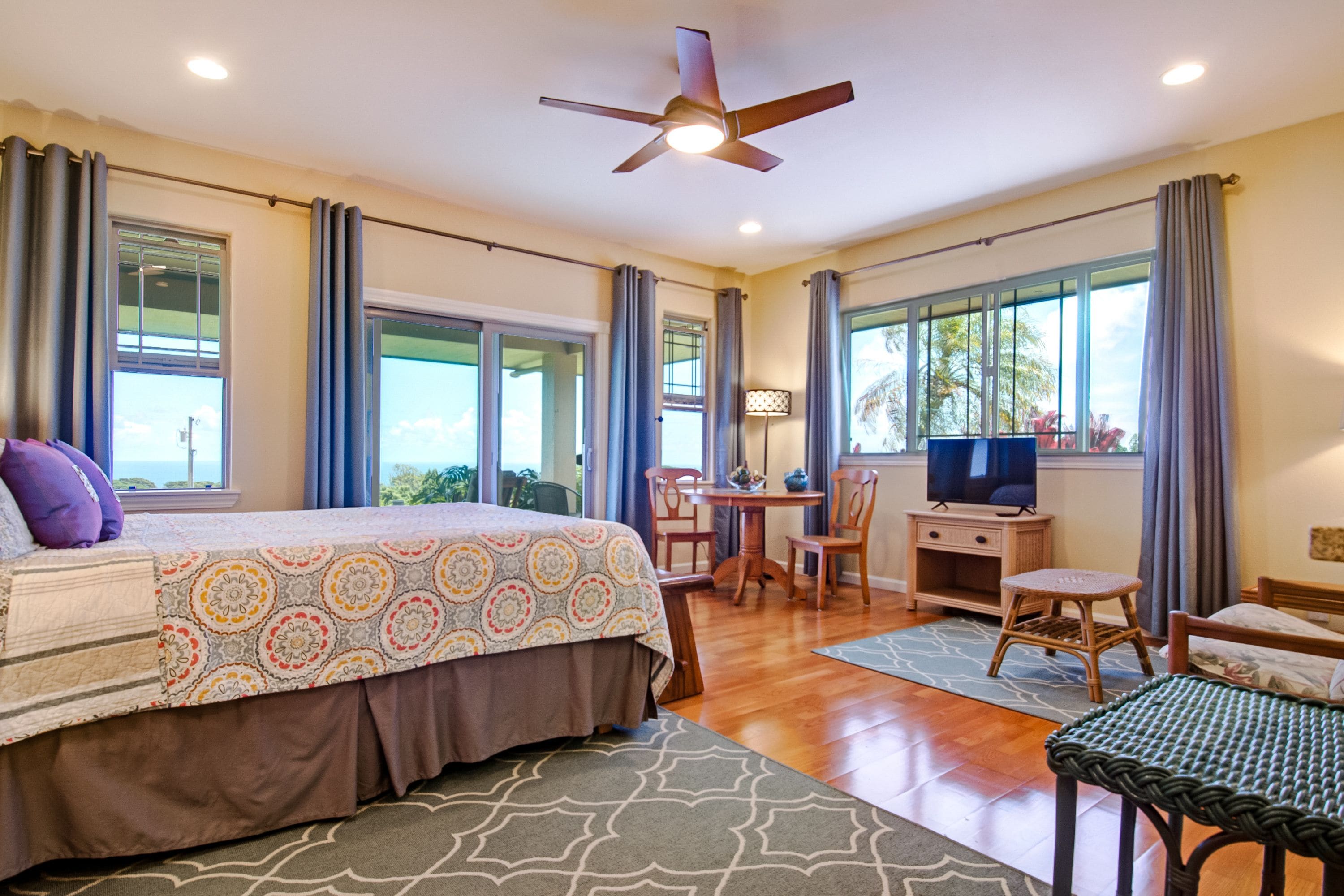 A spacious bedroom with a large bed, a desk, and a television.