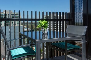 A balcony with a table and chairs, a potted plant, and a view of buildings. - Wyndel Apartments St Kilda Views (Melbourne)