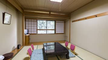 A traditional Japanese room with tatami flooring, a low wooden table, and a shoji screen window.