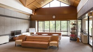 A spacious lounge area with a high ceiling, a large window, and a traditional Japanese tea set display. - Inuyama International Youth Hostel (Inuyama)