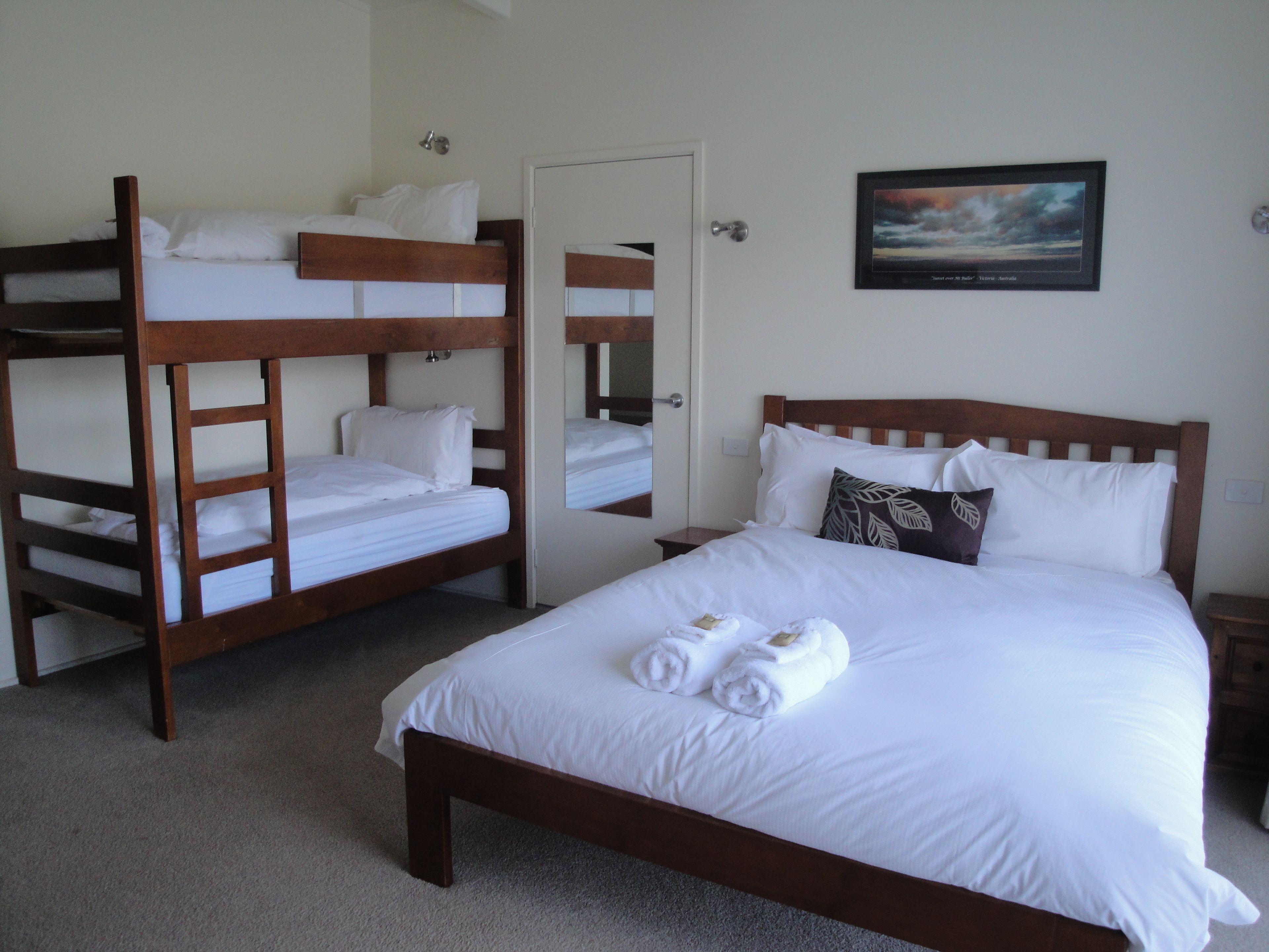 Una habitación de hotel con una litera, una cama individual y un cuadro en la pared.