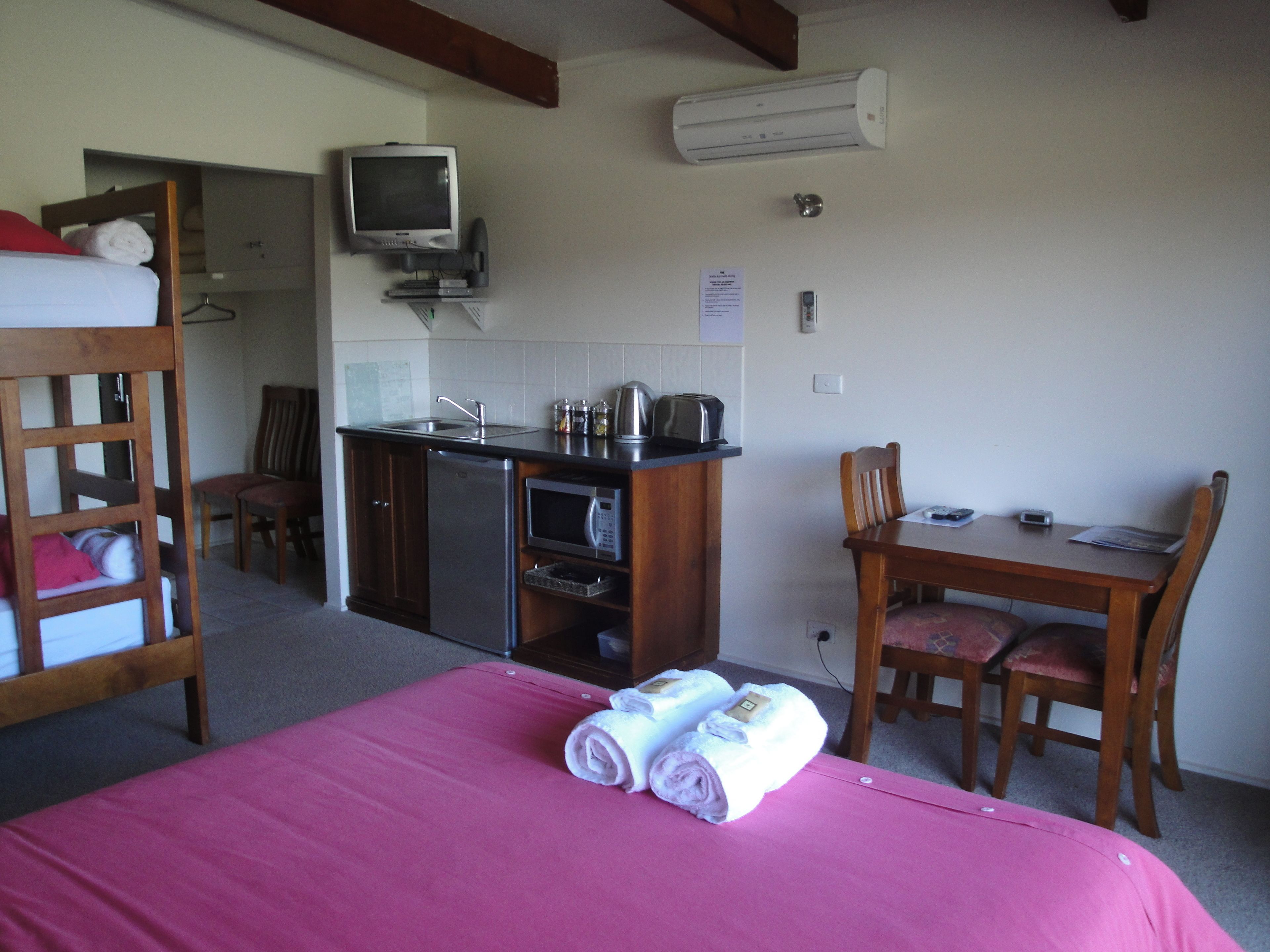 Una habitación compacta con literas, kitchenette, televisión y comedor.