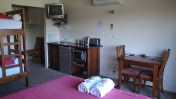 Una habitación compacta con literas, kitchenette, televisión y comedor.