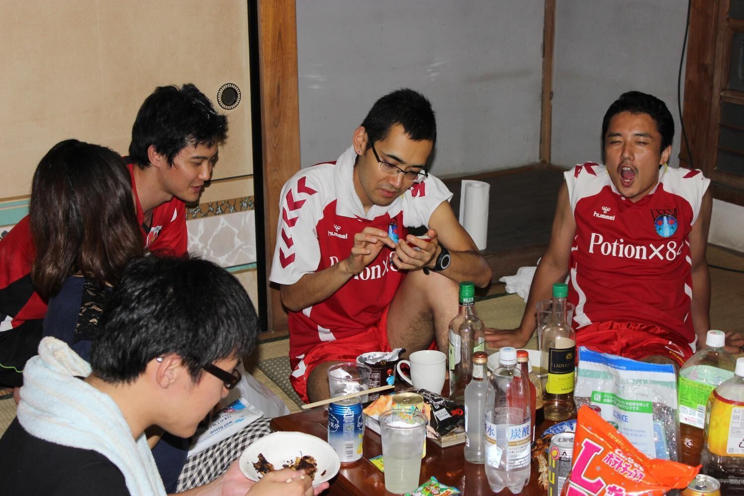 A group of people sitting around a table with various food items and drinks.