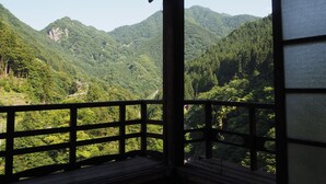 A room with a wooden balcony overlooking a mountainous landscape. - Guest House Nishiki - Hostel (Chichibu)