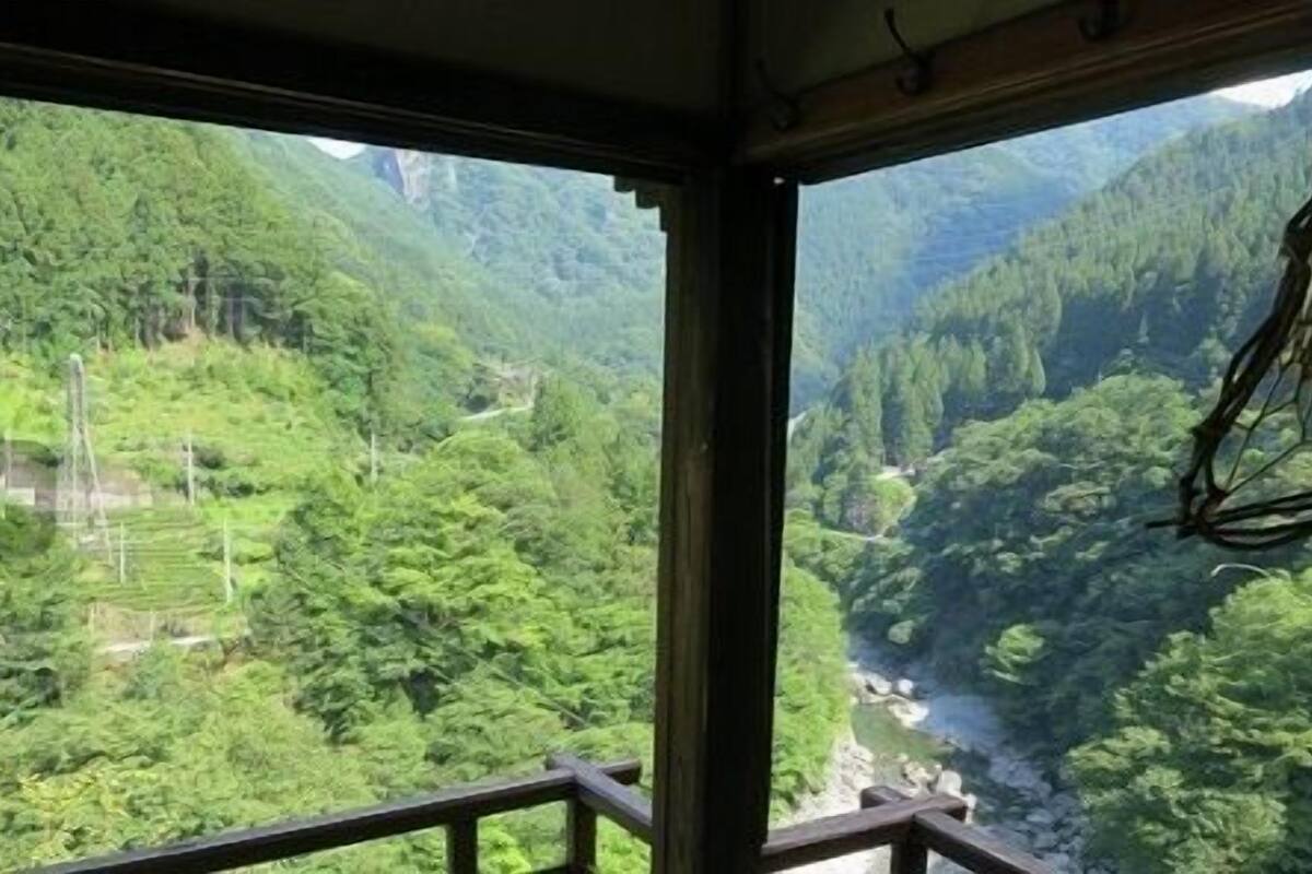 A room with a view of a lush green valley and a river.