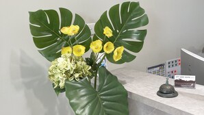 Een zwarte tafel met een vaas vol gele bloemen en groene bladeren.