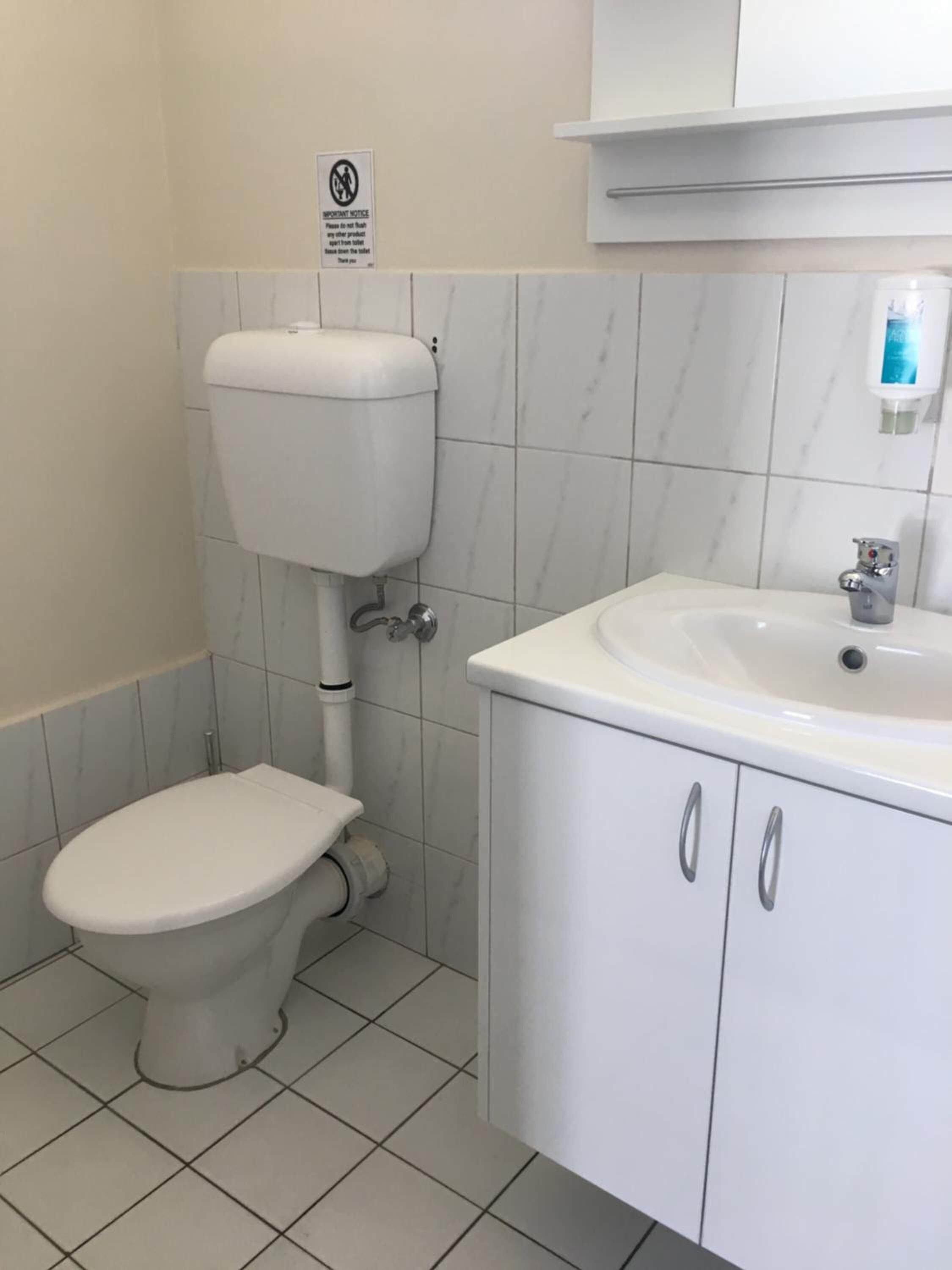 A bathroom with a toilet, sink, and cabinet.