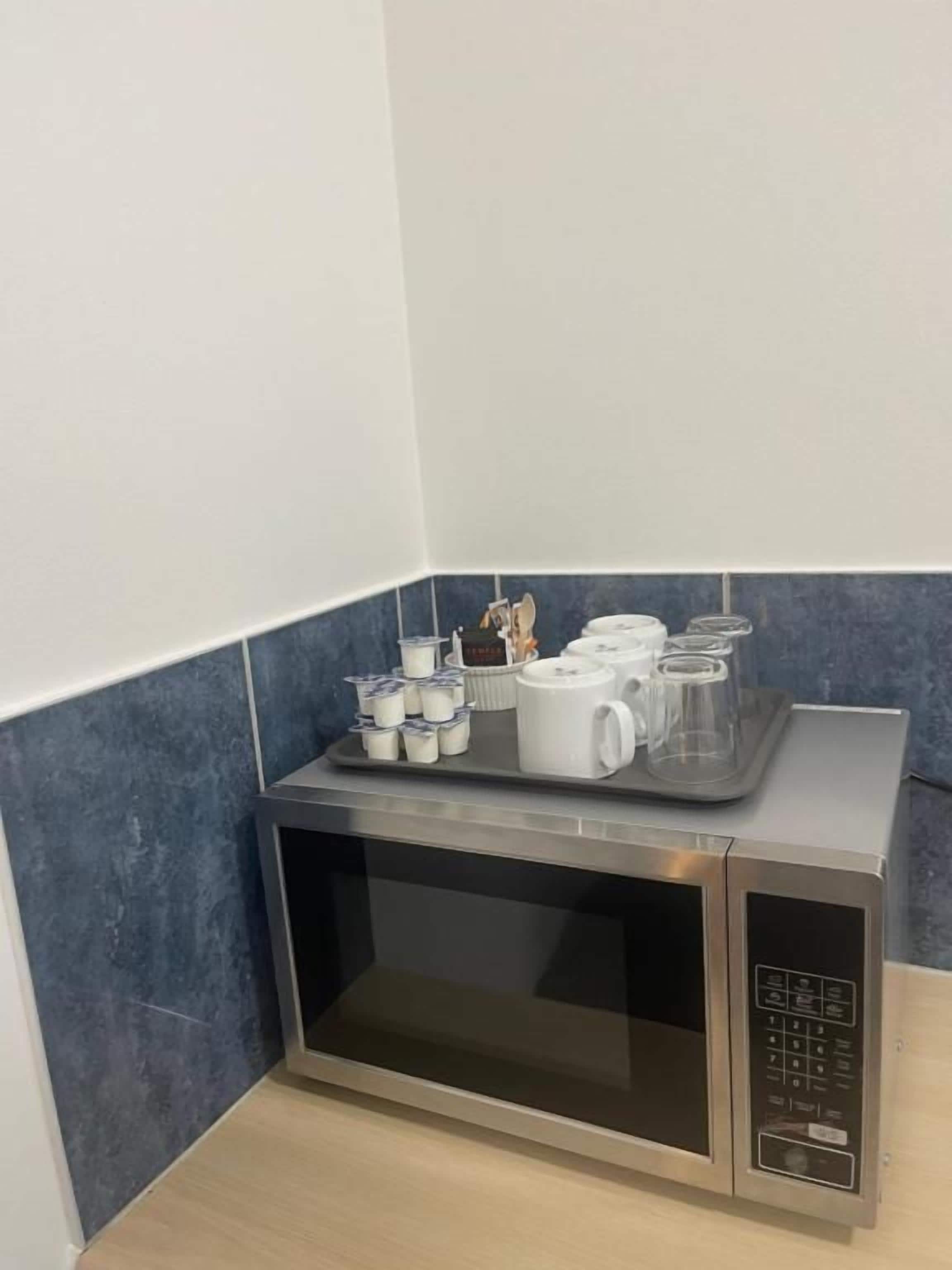 Forno de micro-ondas com uma bandeja contendo canecas e recipientes.
