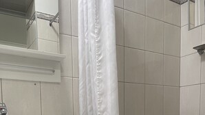 Een badkamer met een witte wastafel, spiegel en douchegordijn.